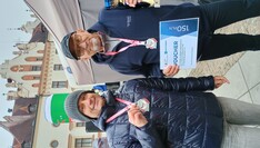Dwóch biegaczy z medalami, a jeden trzyma puchar i dyplom